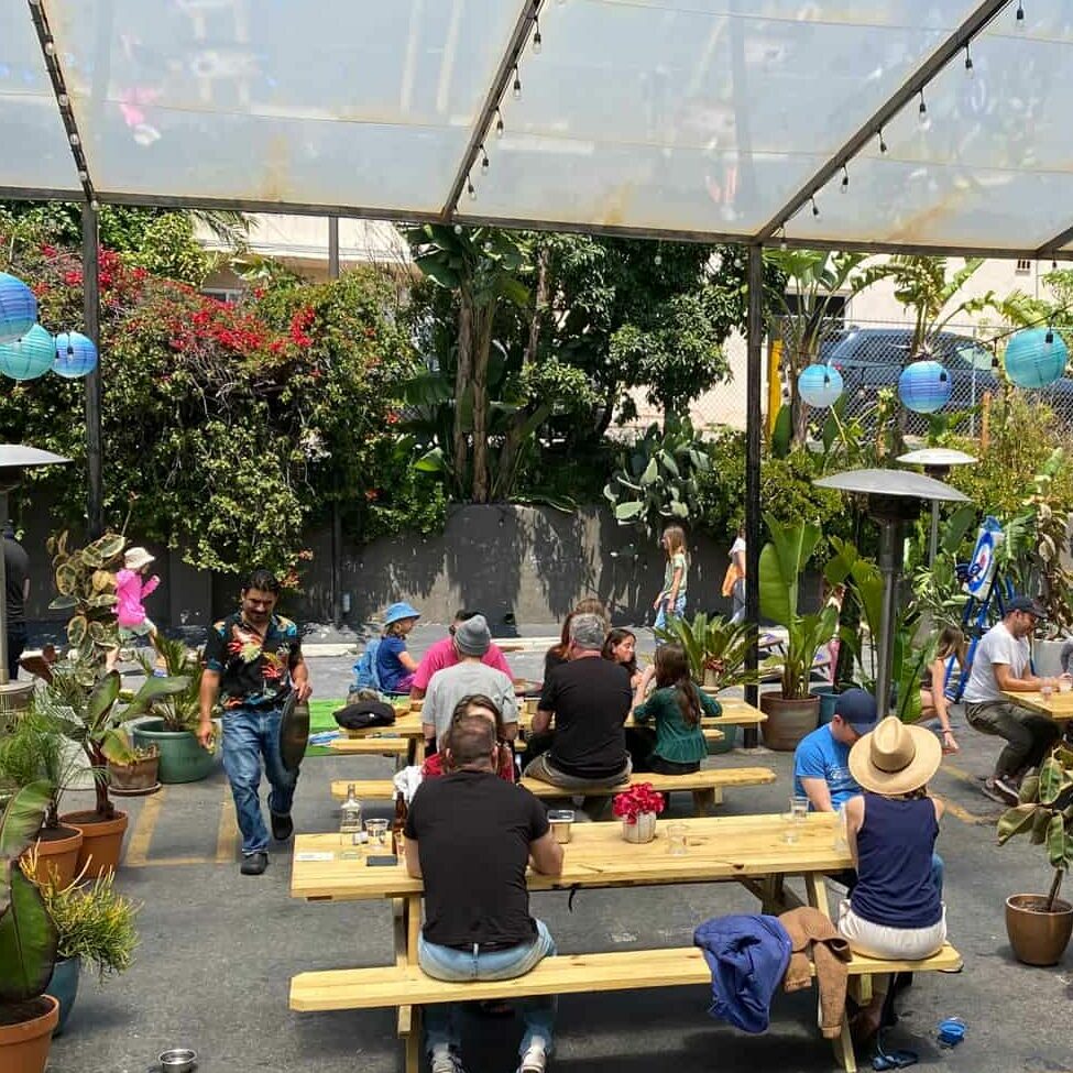 our outdoor patio filled with customers, green plants and blue lanterns